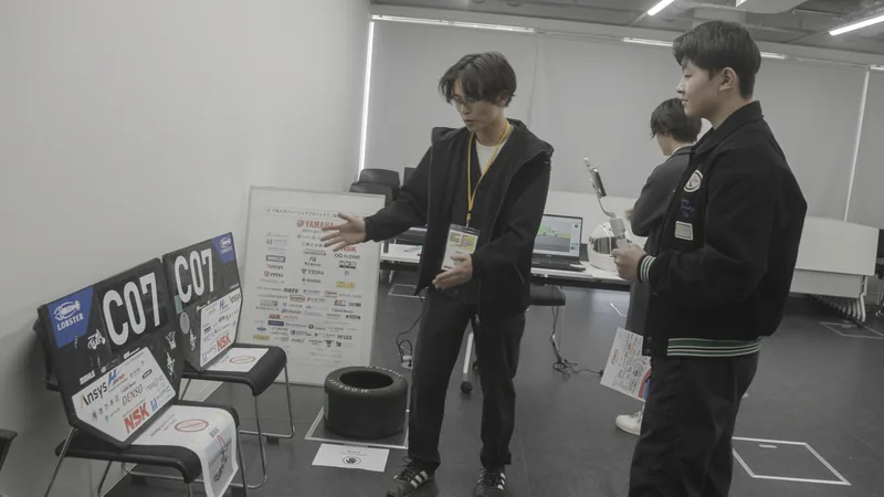 Visitors listening to Chiba University Formula Project students in front of vehicle parts and panels