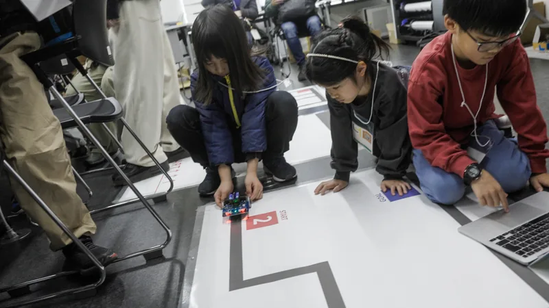 Children checking how a small robot moves along a course