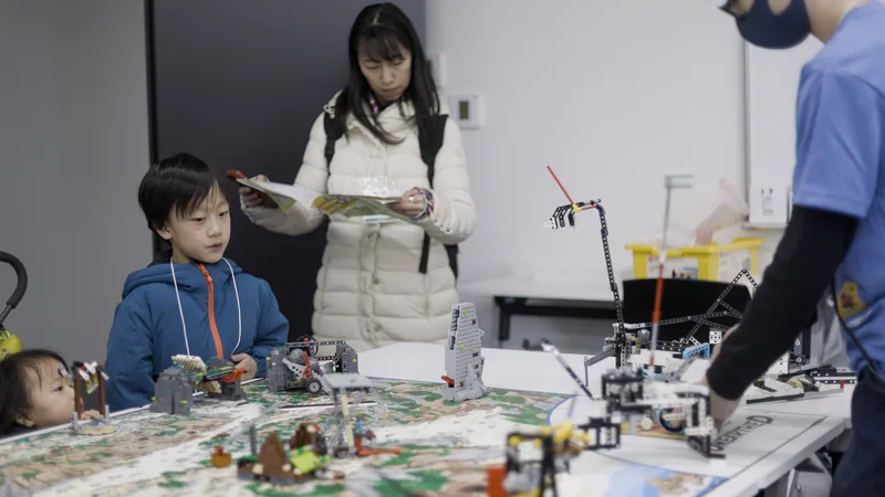 A child watching a student demonstrate a LEGO robot