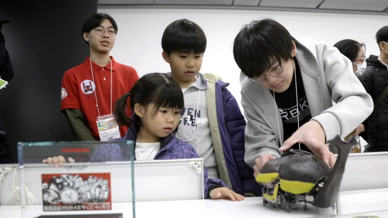 高専生が、自分たちでつくったカブトムシ型ロボットを子どもたちに見せている様子