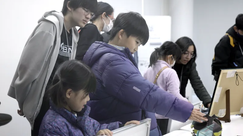 Children reaching out to touch a beetle-shaped robot built by KOSEN students