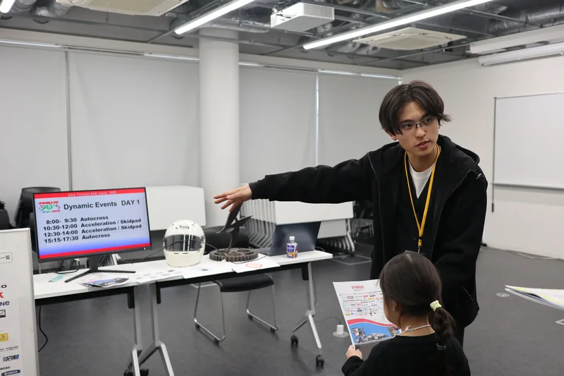 A university student explaining vehicle parts to a child